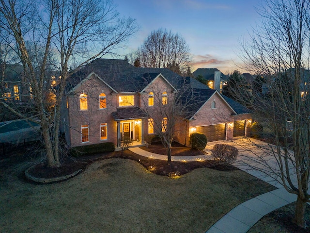 traditional-style home featuring driveway, an attached garage, and a lawn