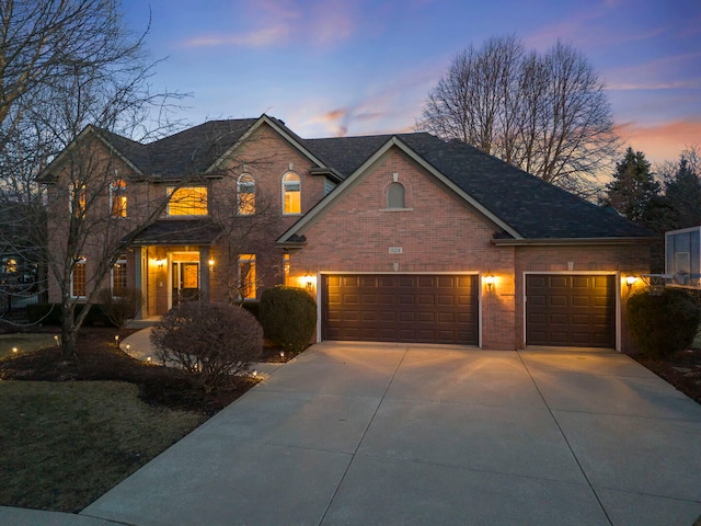 traditional-style home featuring a garage, concrete driveway, and brick siding