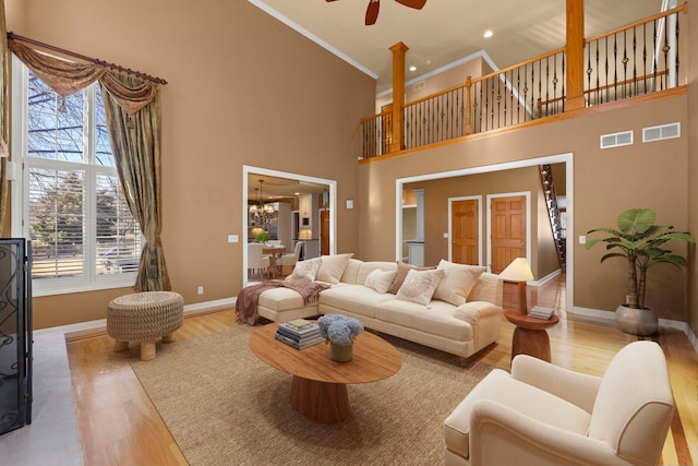 living area with baseboards, crown molding, visible vents, and wood finished floors