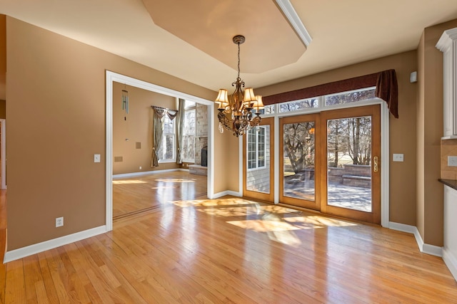 unfurnished dining area featuring a notable chandelier, baseboards, and light wood-style floors