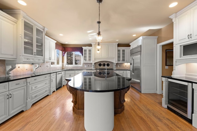 kitchen with stainless steel appliances, dark countertops, beverage cooler, and light wood-type flooring