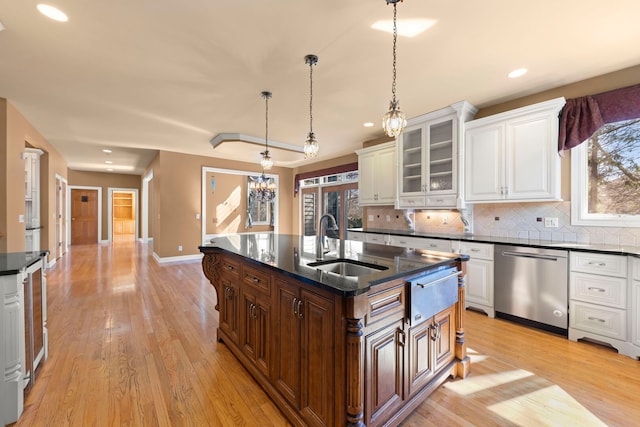 kitchen featuring a warming drawer, light wood-style flooring, decorative backsplash, stainless steel dishwasher, and a sink