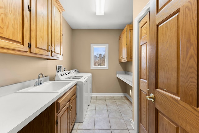 laundry room with cabinet space, baseboards, separate washer and dryer, a sink, and light tile patterned flooring