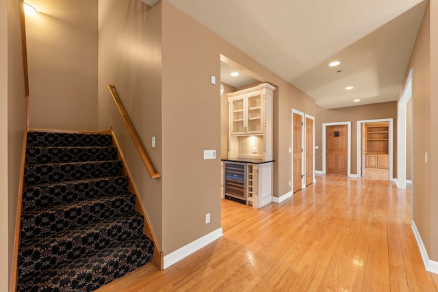 stairs featuring recessed lighting, beverage cooler, baseboards, and wood finished floors