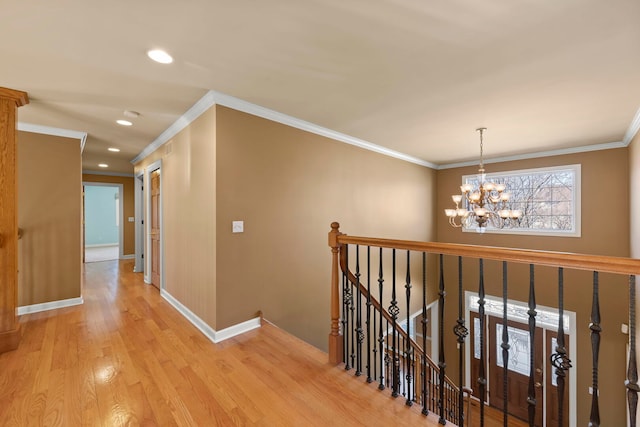 hallway featuring crown molding, an upstairs landing, baseboards, light wood-type flooring, and an inviting chandelier