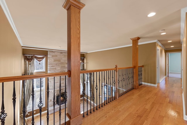 hallway featuring crown molding, baseboards, wood finished floors, and ornate columns