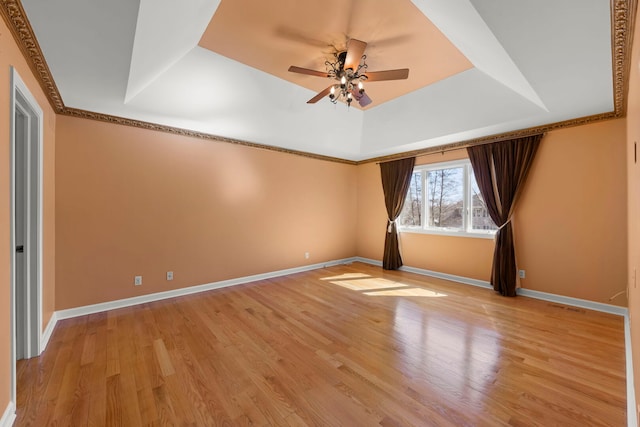 spare room with baseboards, a tray ceiling, a ceiling fan, and light wood-style floors