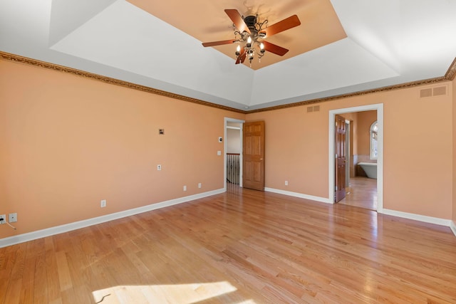 unfurnished room featuring visible vents, a tray ceiling, light wood-style flooring, and baseboards