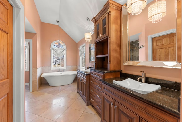 bathroom with lofted ceiling, a wainscoted wall, tile patterned floors, a freestanding bath, and vanity