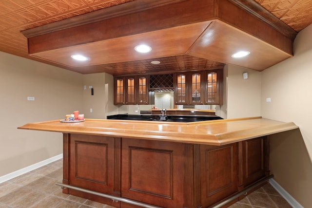 bar with an ornate ceiling, indoor wet bar, recessed lighting, baseboards, and tile patterned floors