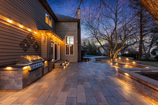 patio terrace at dusk featuring a grill and area for grilling