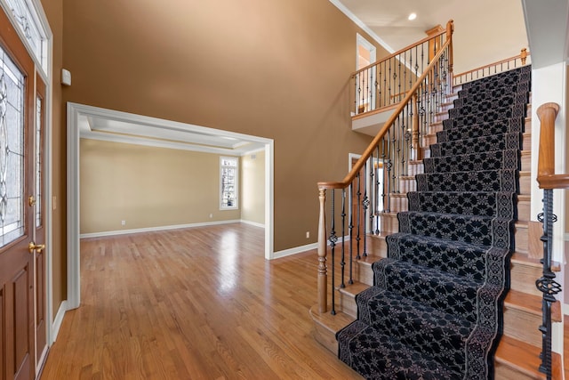 foyer with stairway, wood finished floors, a towering ceiling, and baseboards