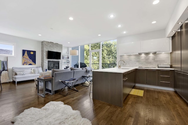 kitchen with dark brown cabinetry, a peninsula, white cabinetry, light countertops, and modern cabinets