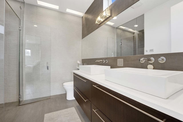 bathroom with a skylight, a sink, a shower stall, and toilet