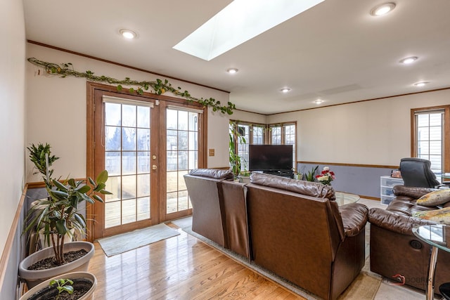 living room with a skylight, crown molding, french doors, light wood-type flooring, and recessed lighting