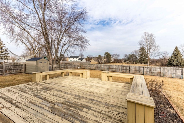 deck with a storage shed, a fenced backyard, and an outbuilding