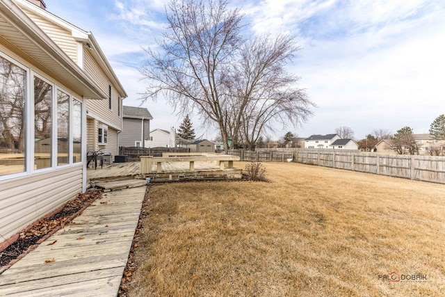 view of yard featuring a deck, a fenced backyard, and a residential view