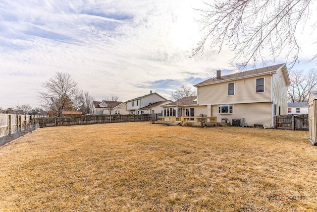 rear view of house featuring a yard, a chimney, central AC unit, a fenced backyard, and a wooden deck