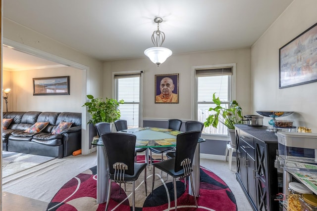 dining space featuring baseboards, ornamental molding, light colored carpet, and a healthy amount of sunlight