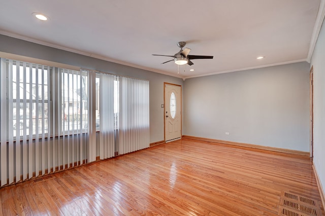 spare room with baseboards, visible vents, ceiling fan, ornamental molding, and hardwood / wood-style floors