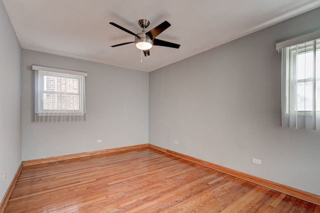 spare room with baseboards, light wood-type flooring, and a healthy amount of sunlight