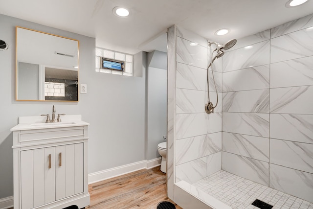 full bath with visible vents, a tile shower, vanity, and baseboards