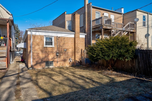 view of side of property featuring brick siding and fence