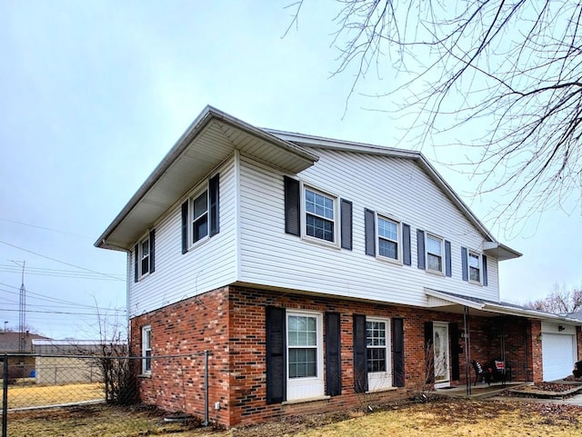 view of front of property featuring brick siding, fence, and an attached garage