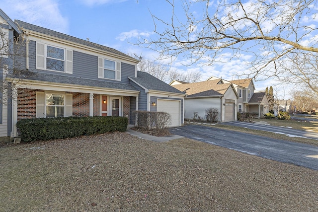 traditional-style home featuring aphalt driveway, brick siding, a shingled roof, and an attached garage