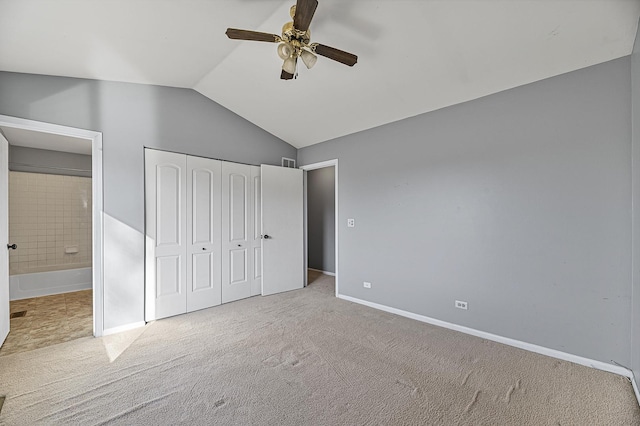 unfurnished bedroom featuring ensuite bathroom, baseboards, vaulted ceiling, a closet, and carpet