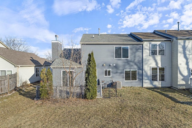 rear view of house with a yard, cooling unit, and fence