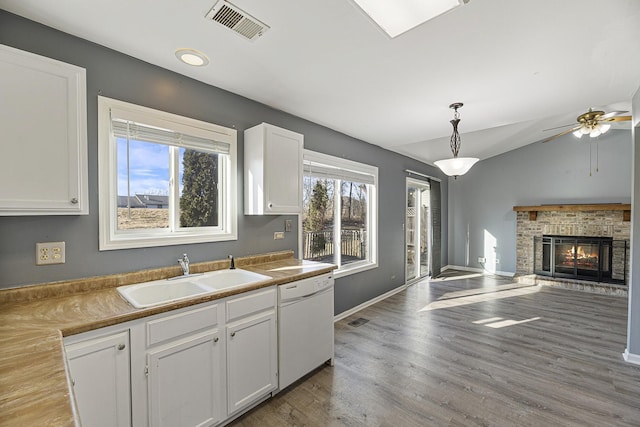 kitchen with visible vents, white cabinetry, vaulted ceiling, a sink, and dishwasher