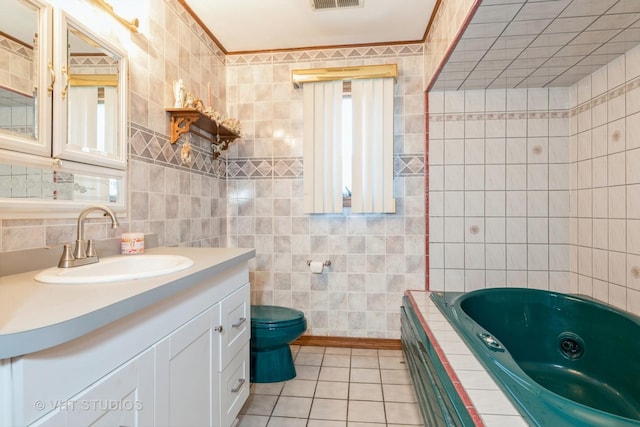 full bath with tile walls, toilet, vanity, tile patterned flooring, and a tub with jets