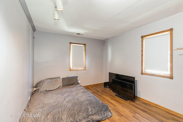 bedroom featuring wood finished floors, visible vents, and baseboards