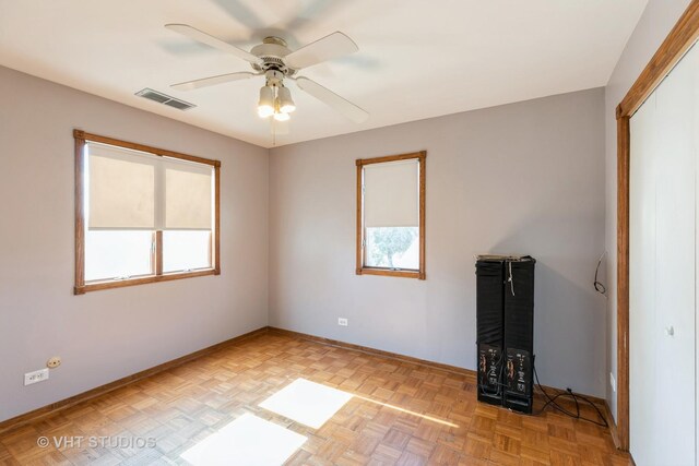 spare room featuring baseboards, visible vents, and a ceiling fan