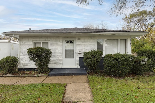 bungalow-style home with a shingled roof and a front lawn