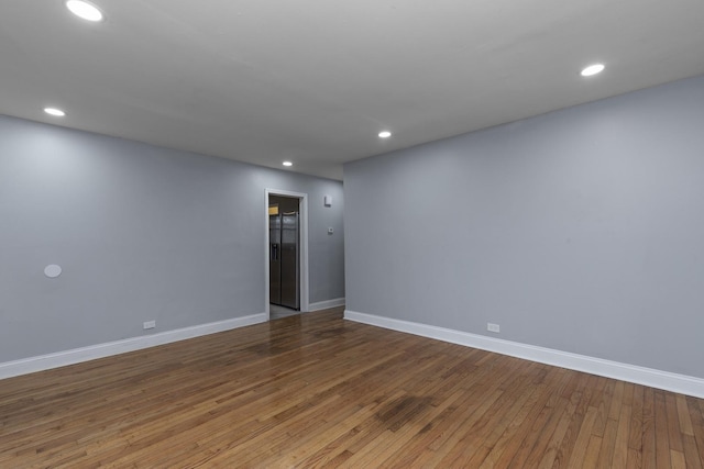 empty room featuring baseboards, hardwood / wood-style flooring, and recessed lighting