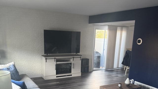 living area featuring brick wall, wood finished floors, and a fireplace