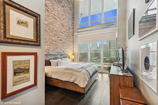 bedroom with a towering ceiling and wood finished floors