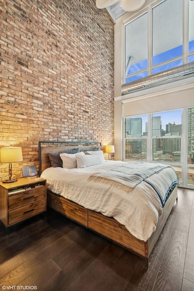 bedroom featuring wood-type flooring, a high ceiling, access to outside, and a city view