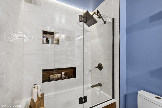 bathroom featuring combined bath / shower with glass door and toilet