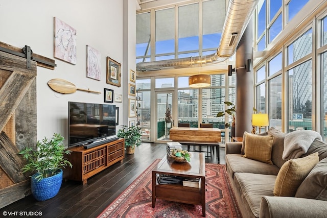 interior space with a towering ceiling, a barn door, and wood finished floors