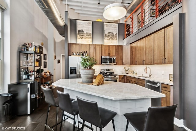 kitchen with tasteful backsplash, a kitchen island, dark wood-type flooring, a high ceiling, and stainless steel appliances