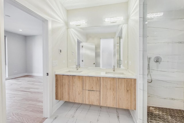 full bath featuring double vanity, a sink, and a marble finish shower