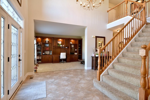 foyer entrance with baseboards, a high ceiling, a chandelier, and stairs