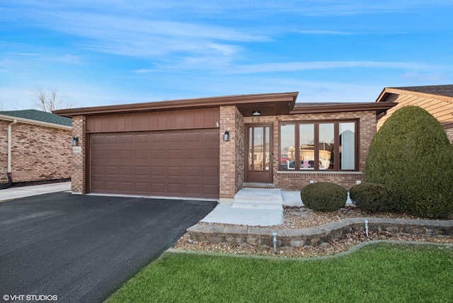 view of front facade featuring an attached garage, aphalt driveway, and brick siding