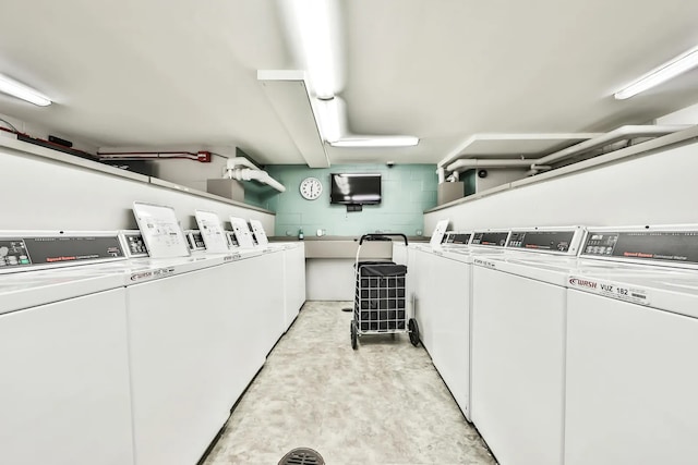 common laundry area with washer and dryer and concrete block wall