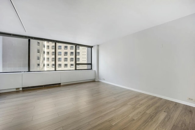 spare room with baseboards and wood finished floors