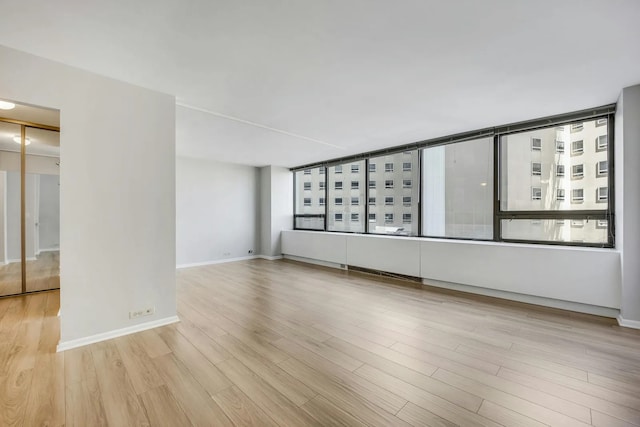 unfurnished room featuring a healthy amount of sunlight, baseboards, and wood finished floors