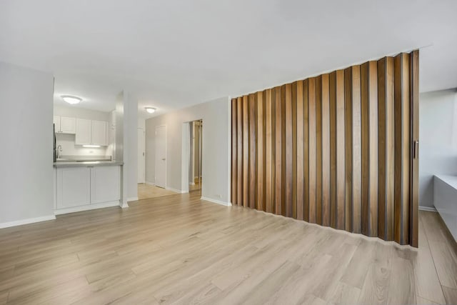 unfurnished living room with light wood-style flooring and baseboards